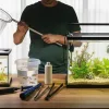 A man is upgrading his fish tank by switching fish and stuff to a bigger tank.