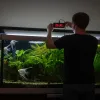 A man is adjust the timer on aquarium light for his fish tank.